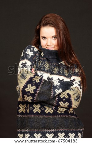 young cute woman in warm winter sweater isolated on dark background