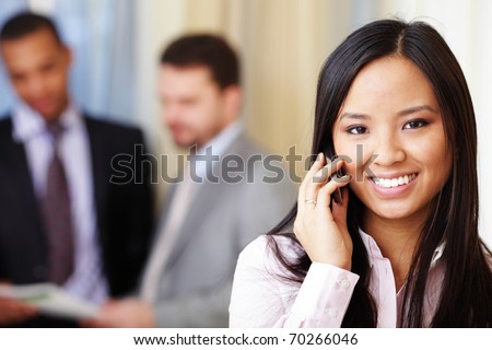 Portrait of young happy asian woman on phone with her business partners on the background