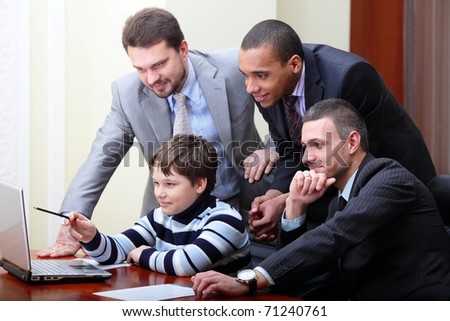 Kid boy explains multi ethnic business team how to work