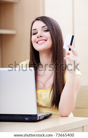 Beautiful young woman shopping on-line with credit card and laptop