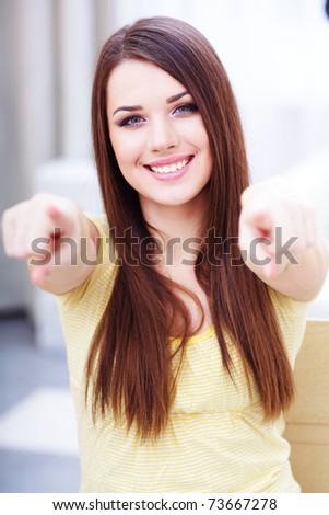 Portrait of a young beautiful casual woman pointing at you