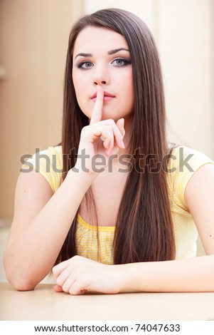 Photo of thoughtful young woman showing silence sign at home