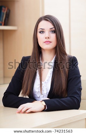 Portrait of a young serious businesswoman sitting near the table in office