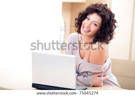 Very happy and cheerful young lady sitting at the table with a laptop
