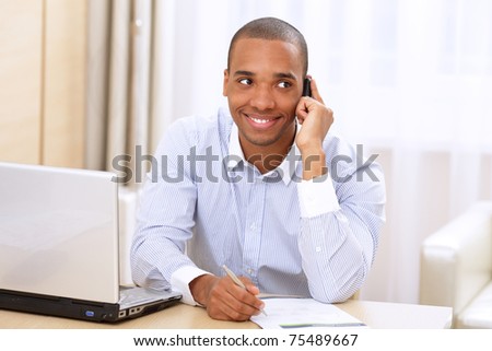 Young smiling african-american businessman calling on phone