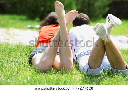 Closeup photo of legs of lying couple lying on the grass