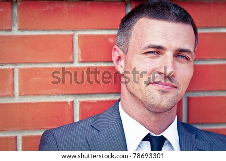 Closeup portrait of a handsome businessman against red brick wall
