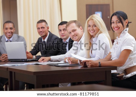 Smiling latin business woman with her business team looking at camera