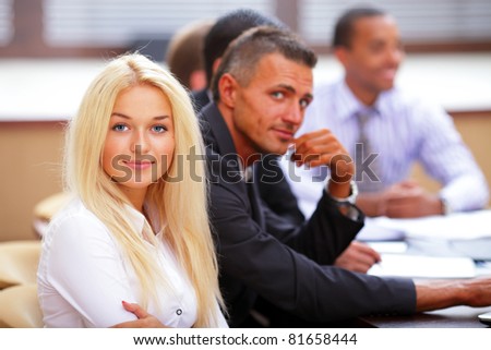Portrait of young happy caucasian woman with her business partners on the background