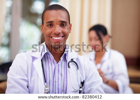Smiling african-american doctor making with colleagues behind
