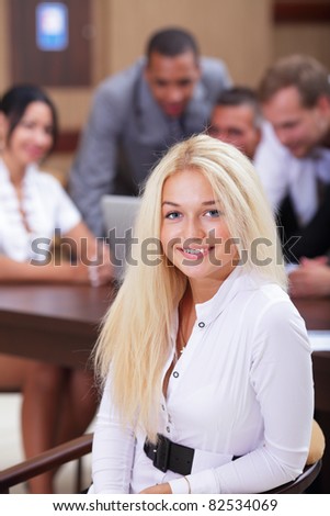 Portrait of a young happy woman with her colleagues working behind