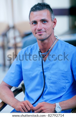 Portrait of a mature handsome doctor in blue scrubs with stethoscope