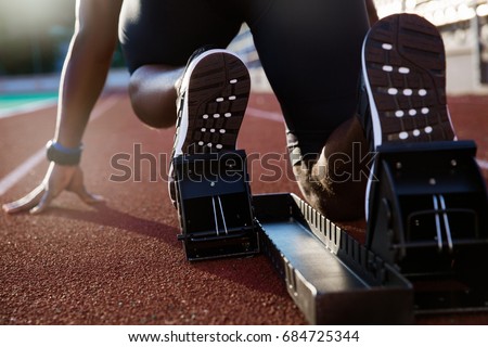 Back view of men\'s feet on starting block ready for a sprint start