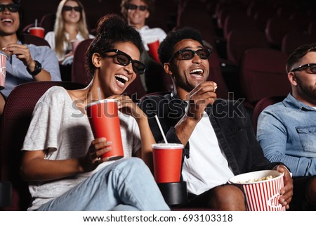 Picture of happy friends sitting in cinema watch film eating popcorn and drinking aerated sweet water.
