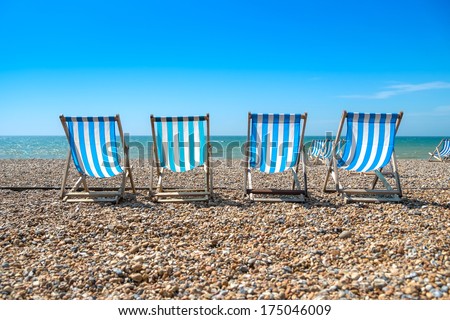 4 blue deck chairs on a pebble beach