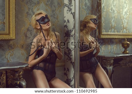 Pretty woman in lingerie and mask near the mirror