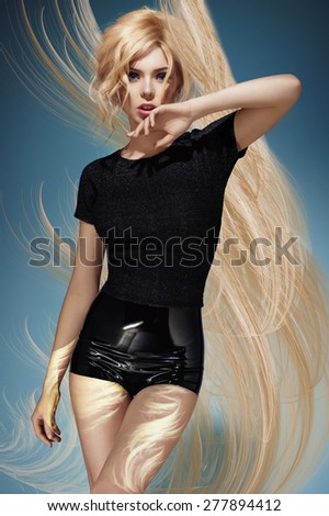 Blonde model in a black blouse and latex shorts on blue background