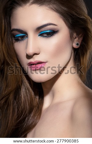 Glamour close-up portrait of beautiful woman model face with winged bright blue eyeliner make-up