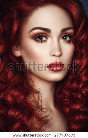 Portrait of beautiful redhead woman with wavy hair and green eyes looking at camera