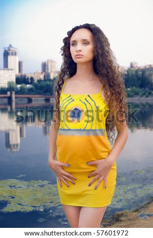 stock-photo-young-women-in-yellow-outfit-on-river-and-city-background-57601972.jpg