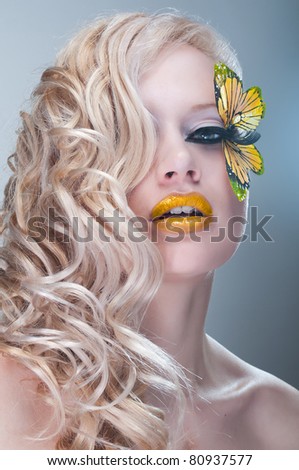 Blonde curly woman with yellow butterfly on lashes