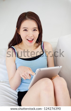 Young Asian woman using a pad PC in the sofa