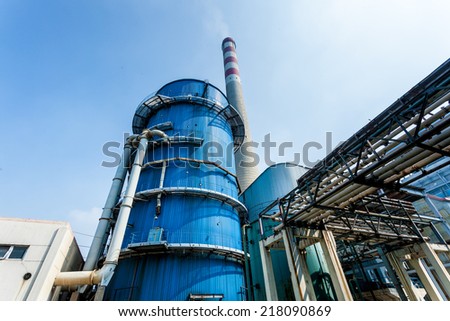 factory with main chimneys expelling smoke into a deep blue sky