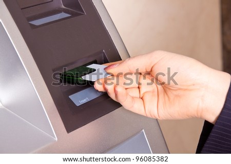 Closeup of a woman\'s had swiping a debit card through a scanner. Shallow depth of field.