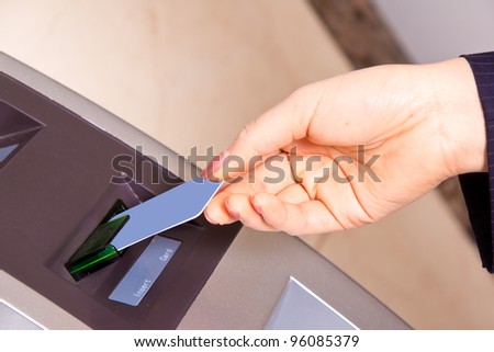 Closeup of a woman\'s had swiping a debit card through a scanner. Shallow depth of field.