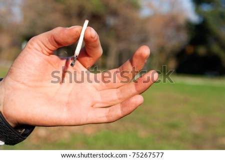 Hand with dirty fingers holding a marijuana cigarette