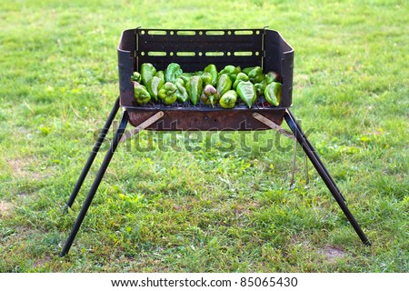 Green peppers baking on a barbecue outside on the grass