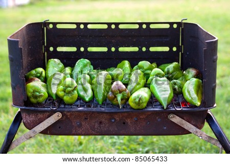 Green peppers baking on a barbecue outside on the grass