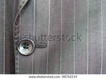Close detail of a button on a pin striped business suit coat