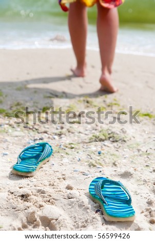 Flip-flops on beach. Woman going for a swim on a  beach. Focus on shoes