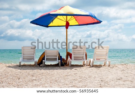 Four white deck chairs and big umbrella on the beach near sea