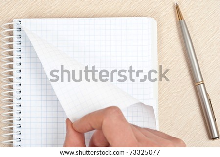 Hand tearing one paper page from notepad on desk