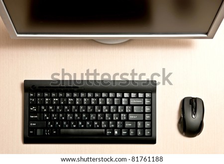 Black keyboard, mouse and monitor on a wood desk.