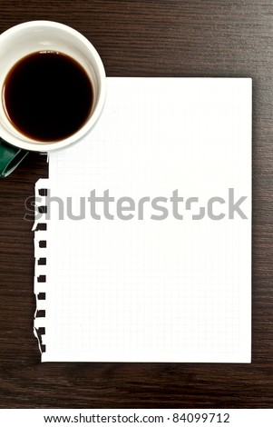 Cup of coffee and blank paper on dark desk