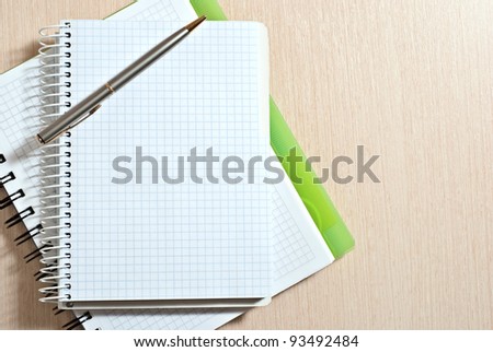 Blank spiral note pad with silver pen on wood desk