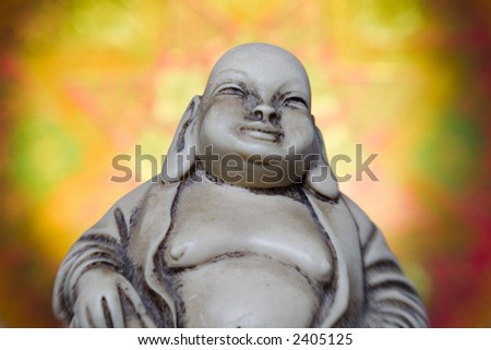 Upper body of a Buddha figurine from asian religion is shown against a glowing eastern style background.
