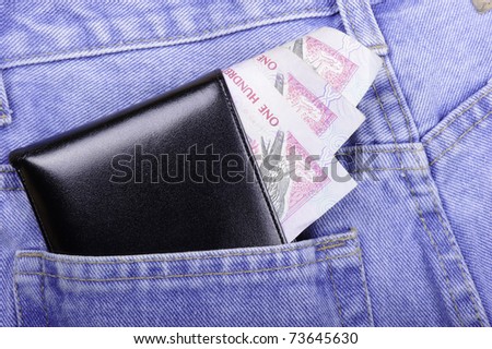 poking out of a wallet in the back pocket of a pair of jeans inviting a pickpocket to steal them
