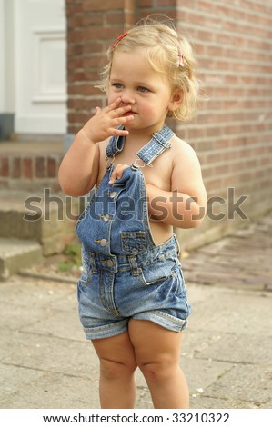 Cute 2 year old girl is standing outside