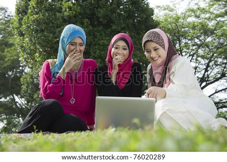 young muslim woman in hijab happy looking at laptop with friends