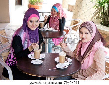 young muslim woman in head scarf drink in cafe with friends