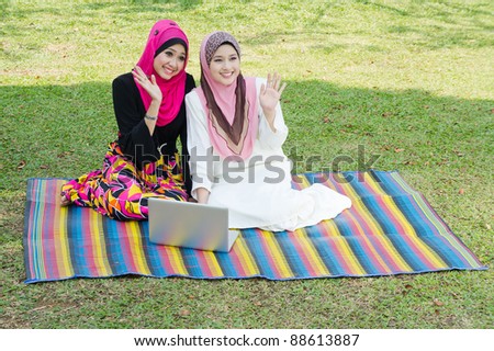 two young muslim woman say hi to their friends at park