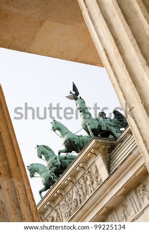 Quadriga Monument at Brandenbourg Gate in Berlin-Germany, viewed through two of twelve Doric columns, in oblique composition. Chariot drawn by 4 horses driven by Victoria, the Roman goddess of Victory
