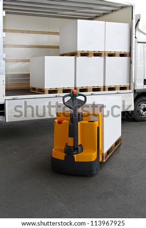 Forklift truck loading pallets of paper in lorry