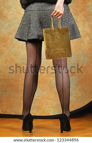 Golden shopping bag and long legs with classic stockings