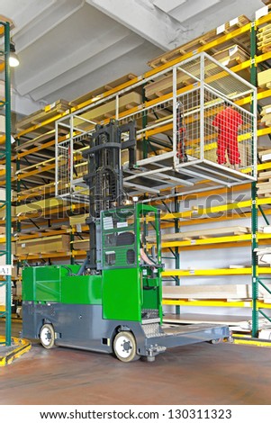 Side loaded forklift with basket in wood warehouse