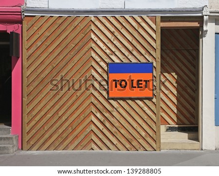 Empty shop with to let sign and wooden barrier